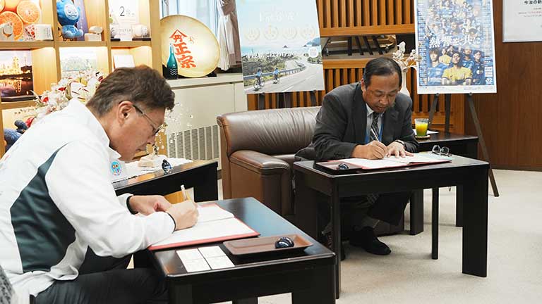 8月18日に今治市役所で行われた協定締結式において協定書に署名するJAえひめエネルギー得能社長（奥）と徳永市長（手前）